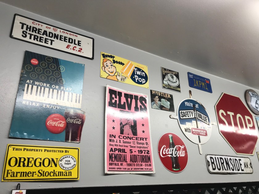 Vintage signs and advertisements adorn the area above the coffee cup display