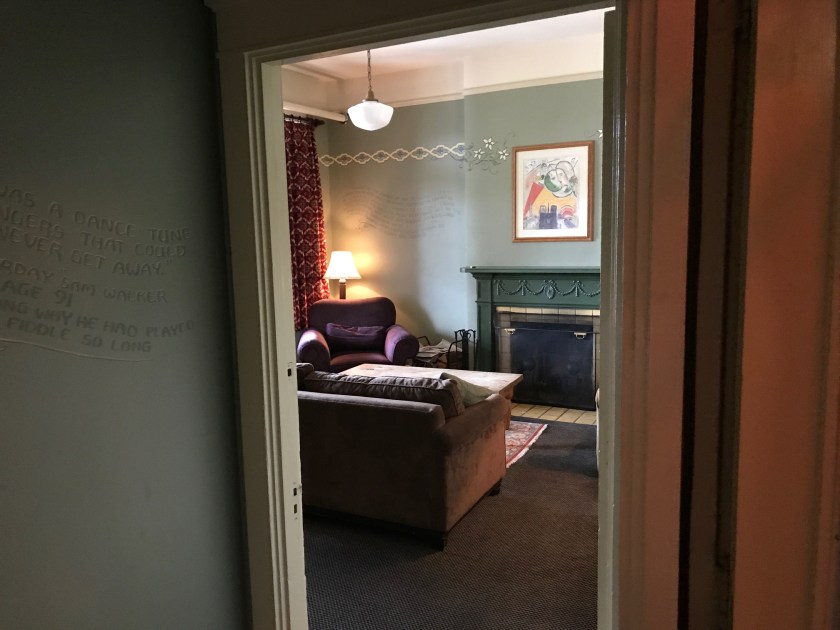 Looking into a room where a lovely couch, fireplace and artwork can be seen