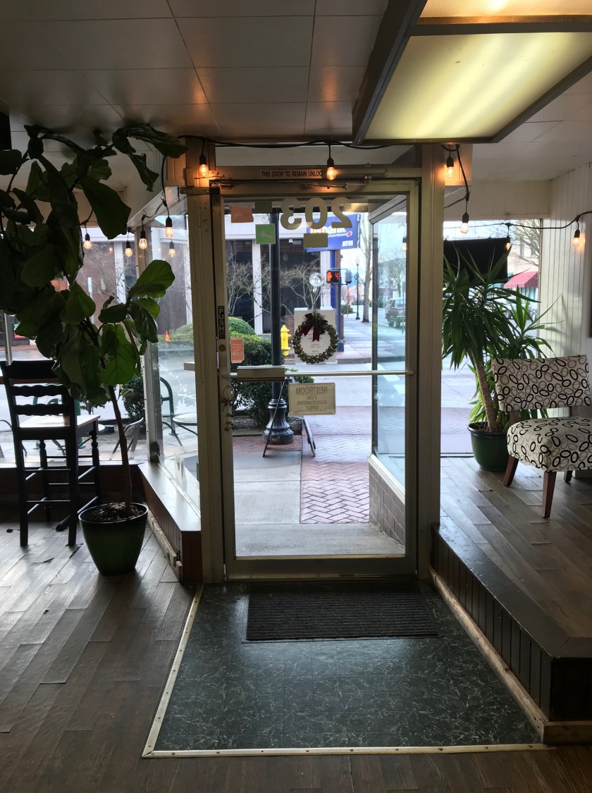 Inside Manaia looking toward the front entrance, large windows can be seen along with counter seating facing the downtown area