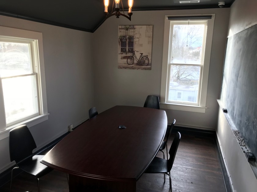 The first room at the top of the stairs has a beautiful dark finished floor, large table for group discussions, and a chalkboard